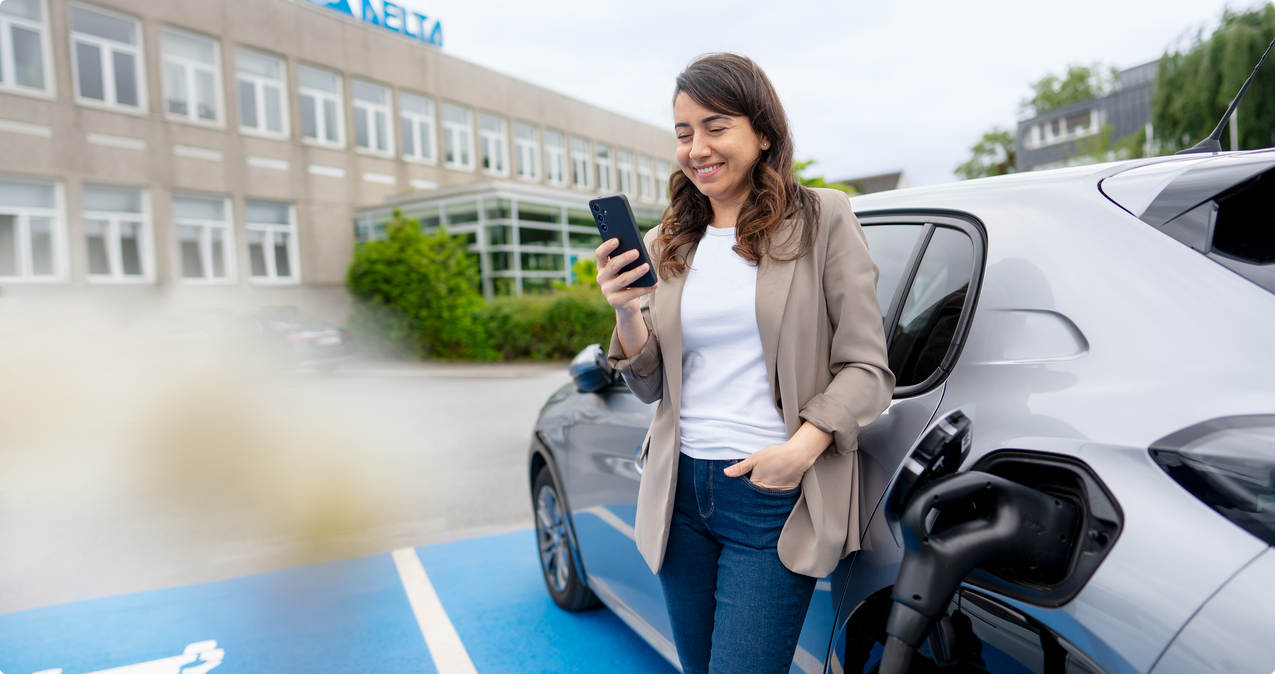 Delta employee beside an electric vehicle at a charging station