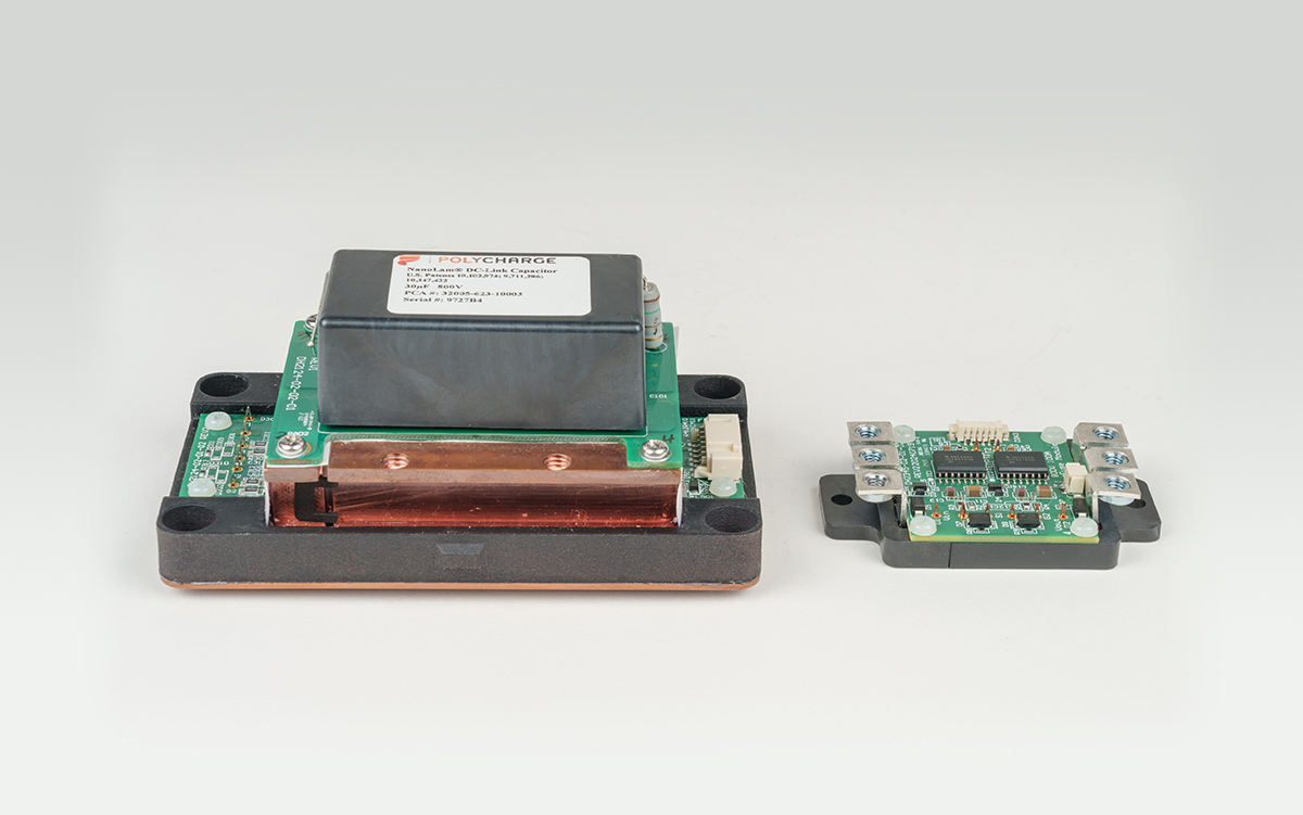 Power eFuse assembly with a large dark module on a copper busbar base and a smaller control circuit board beside it.